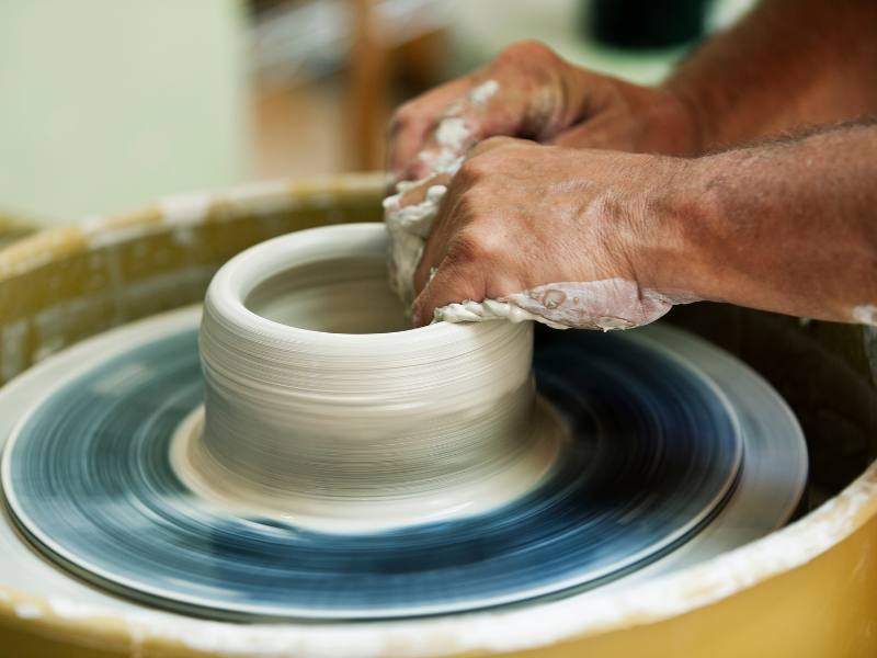 person throwing bowl on pottery wheel